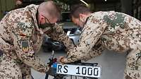 Zwei Soldaten befestigen ein Nummernschild an einem Fahrrad