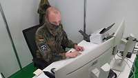 Ein Soldat sitzt am Arbeitsplatz PC