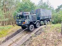 Ein Lastwagen in Flecktarn-Lackierung steht auf einem Hügel.