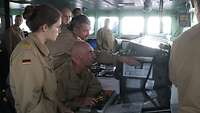 Mehrere Soldatinnen und Soldaten beraten sich und betrachten dabei den Bildschirm mit elektronischer Seekarte