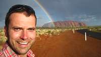 Axel Schönborn hält mit einem Selfie den Zwillingsregenbogen vor dem Ayers Rock fest