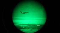 Blick durch den Restlichtverstärker eines Piloten. Auf dem runden, grünen Bildausschnitt ist ein anderes Flugzeug zu sehen.