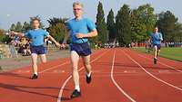 Drei Soldaten in Sportkleidung laufen über eine Tartanbahn.