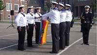 Sechs Matrosen haben ihre Hand auf eine deutsche Flagge gelegt.