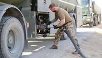 Ein Soldat schließt einen Schlauch vom Tanklager am Flugfeldtankwagen an