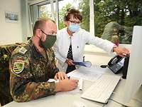 Ärztin steht neben einem Soldaten, der am Schreibtisch sitzt, und zeigt auf dem Bildschirm.