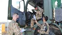 Zwei Soldaten überprüfen die Papiere eines im Führerhaus sitzenden Fahrers eines Bundeswehr-Lkws 