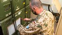 Ein Soldat schraubt ein Lüftungsgitter am Netzwerkschrank ab