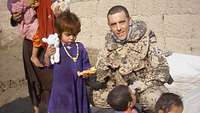 EIn Soldat kniet neben Kinder