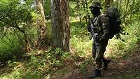 Ein Soldat läuft mit seiner Ausrüstung durch einen Wald