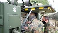 Two soldiers working at the antenna.