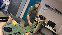 Ein wasserdichter Overall eines Eurofighterpiloten wird von einem Techniker der Fachgruppe RTS gezeigt und erklärt.