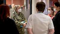 Eine Soldatin spricht zu Mitarbeiterinnen des Pflegepersonals