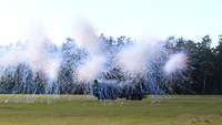 A vehicle on a field, a smoke screen building up in front of it.