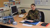 Oberfeldarzt Dreyer sitzt in Flecktarnuniform an ihrem Schreibtisch