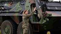 Die Soldatin steigt in ihren Panzer ein.