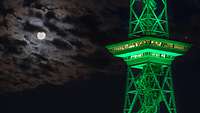 Ein Turm wird bei Nacht grün angeleuchtet.