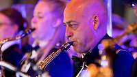 Ein niederländischer Soldat spielt Saxophon, neben ihm sitzen weitere Band-Mitglieder.