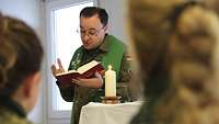 Militärpfarrer Petro Stanko liest aus der Bibel, vor ihm auf dem Altar steht eine brennende Kerze
