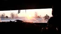 Der Blick aus durch die Frontscheibe eines gepanzerten Fahrzeugs in den Sonnenaufgang.