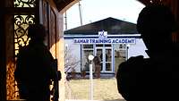 Aus einer geöffneten Tür fällt der Blick auf einen Flachbau mit der Aufschrift „Bawar Training Academy“