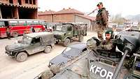 Bundeswehr soldiers and vehicles with the inscription KFOR on a street