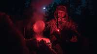 Ein Soldat schmilzt bei Dunkelheit und rotem Licht Schnee in einem Topf.