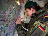 Eine Soldatin markiert mit einem Stift etwas auf einer Lagekarte