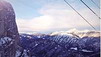 Blick von oben: winterliches Alpenpanorama mit grauen, verschneiten Bergen
