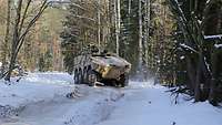 Ein gepanzertes Radfahrzeug steht auf einem Weg in einem verschneiten Wald