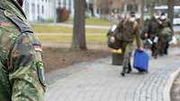 Soldaten mit Reisetaschen laufen den Weg entlang.