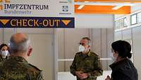 Dr. Baumgärtner steht mit Soldatinnen und Soldaten vor einem Schild Impfzentrum Bundeswehr