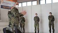 Ein Soldat steht im „Impfzentrum Bundeswehr und unterhält sich mit an-deren Soldatinnen und Soldaten.