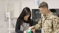 Eine Frau und ein Soldat verwalten gemeinsam die Medikamente im Bereich des Fliegerarztes.