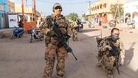 Zwei Soldaten auf einer Straße Malis während einer Patrouille, einer der Soldaten kniet, im Hintergrund Häuser