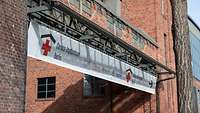 Ein Schild mit der Aufschrift „Corona-Impfzentrum“ hängt am Ausgang eines roten Backsteingebäudes