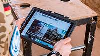 Ein Soldat hält ein Tablet in der Hand. Auf dem Bildschirm steht auf der Website der Bundeswehr: „Ich bin im Einsatz in Mali.“ 