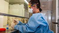 Eine Soldatin arbeitet im Schutzanzug im Labor mit Proben