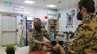 Ein Soldat steht hinter einer Theke und reicht ein Tablett mit Kaffee an einen anderen Soldaten weiter