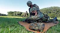 Zwei Soldaten üben mit einer Pistole auf einer Wiese.