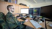 Seitenaufnahme des Soldaten Petzold mit Blick auf seine Computermonitore.