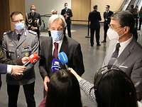 Drei Männer stellen sich den Medien, der mittig stehende Verteidigungsminister spricht in mehrere Mikrofone