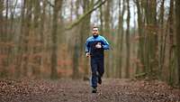 Ein Soldat im Sportanzug beim Lauftraining im Wald.