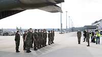 Soldatinnen und Soldaten stehen an der offenen Ladefläche eine Flugzeugs und werden durch einen Generalarzt begrüßt