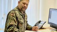Ein Soldat steht an seinem Schreibtisch und schaut in die Kamera 