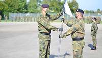 Ein Soldat übergibt die Kompanieflagge an den neuen Chef.