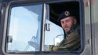 Ein Soldat sitzt in der Fahrerkabine eines Tankwagens und lächelt in die Kamera