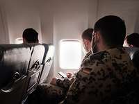 Soldaten sitzen in einem Flugzeug und schauen zur rechten Seite aus dem Fenster hinaus 