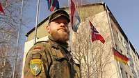 Ein Soldat steht vor einem Haus und vielen Flaggen