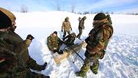 Niederländische und belgische Soldaten präparieren Sprengladungen für verschiedene Baumaterialien auf einer verschneiten Fläche 